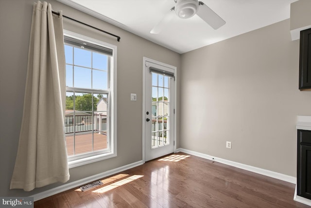 doorway featuring dark wood-type flooring, baseboards, and ceiling fan