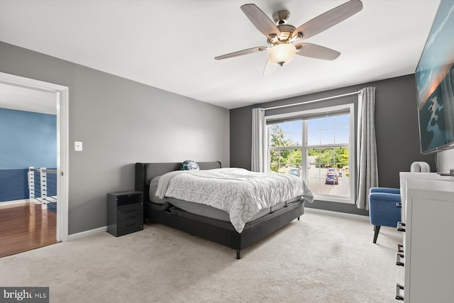 bedroom with light carpet, baseboards, and a ceiling fan