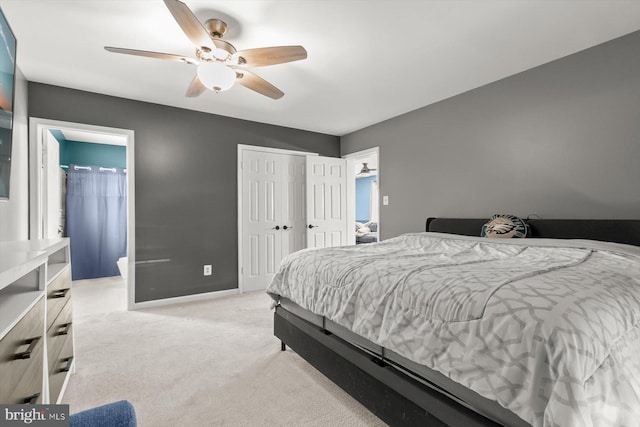 bedroom featuring light colored carpet, a closet, baseboards, a ceiling fan, and ensuite bathroom