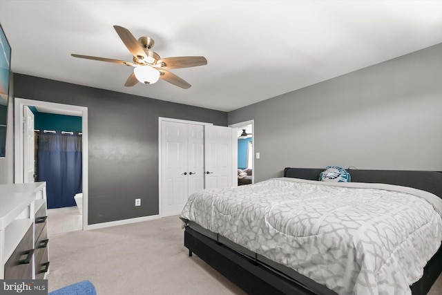 bedroom with light carpet, baseboards, a ceiling fan, and ensuite bath