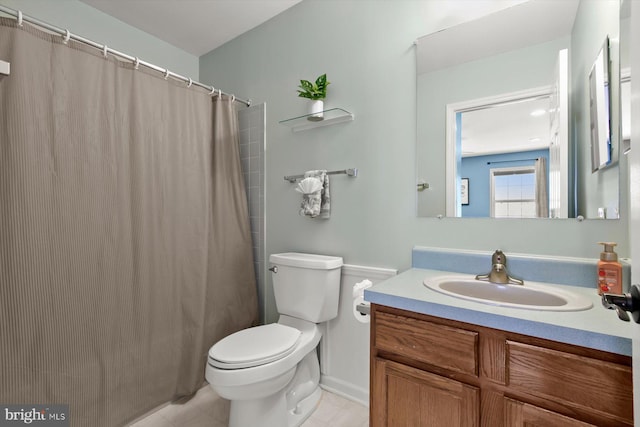 bathroom featuring toilet, vanity, tile patterned floors, and curtained shower