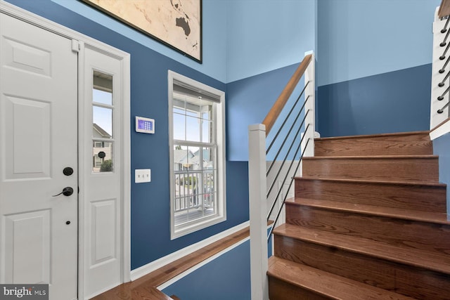 entrance foyer with stairs, wood finished floors, and baseboards