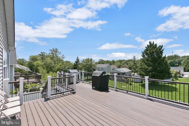 wooden terrace with a lawn and view of wooded area
