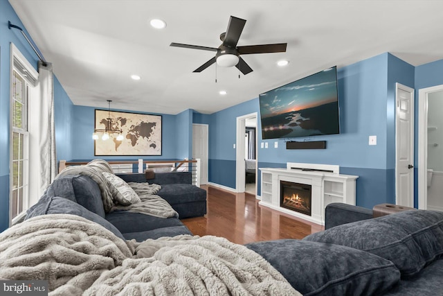 living room with wood finished floors, ceiling fan, recessed lighting, a chandelier, and a lit fireplace