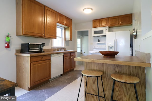250 E Main St, Millheim, PA 16854 - kitchen featuring white appliances, a kitchen breakfast bar, a peninsula, brown cabinetry, and a sink