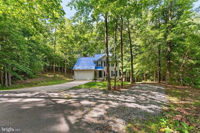 9380 Caucus Dr, King George, VA 22485 - view of front of home featuring driveway, an attached garage, metal roof, and a forest view