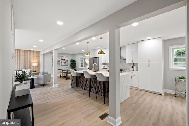 9813 Singleton Dr, Bethesda, MD 20817 - kitchen with light wood-style floors, light countertops, white cabinetry, a kitchen bar, and recessed lighting