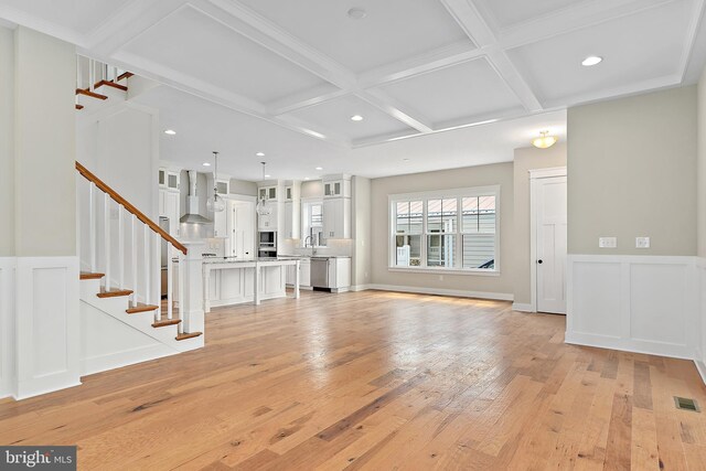 114 Jersey St, Dewey Beach, DE 19971 - unfurnished living room featuring coffered ceiling, light wood-type flooring, stairway, a wainscoted wall, and beam ceiling
