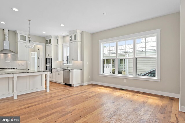 114 Jersey St, Dewey Beach, DE 19971 - kitchen with wall chimney exhaust hood, stainless steel appliances, decorative backsplash, light wood-style floors, and baseboards