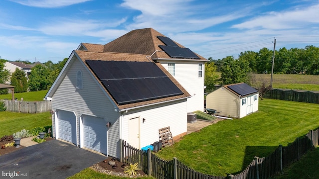 134 Cobblestone Dr, Gilbertsville, PA 19525 - view of side of property featuring roof mounted solar panels, a garage, a shingled roof, central air condition unit, and an outbuilding