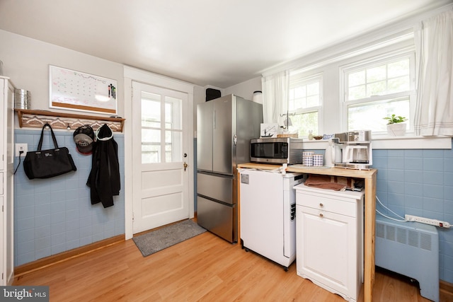 951 Little Conestoga Rd, Glenmoore, PA 19343 - kitchen with radiator heating unit, stainless steel appliances, tile walls, light wood-type flooring, and white cabinetry
