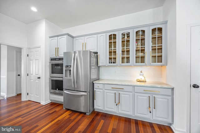 9177 Drawbridge Dr, Delmar, MD 21875 - kitchen with appliances with stainless steel finishes, glass insert cabinets, dark wood-type flooring, light stone counters, and gray cabinetry