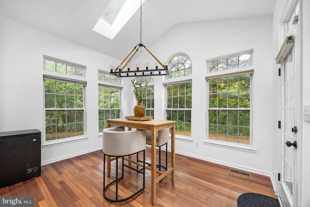 9177 Drawbridge Dr, Delmar, MD 21875 - dining room featuring a skylight, a chandelier, hardwood / wood-style floors, baseboards, and high vaulted ceiling