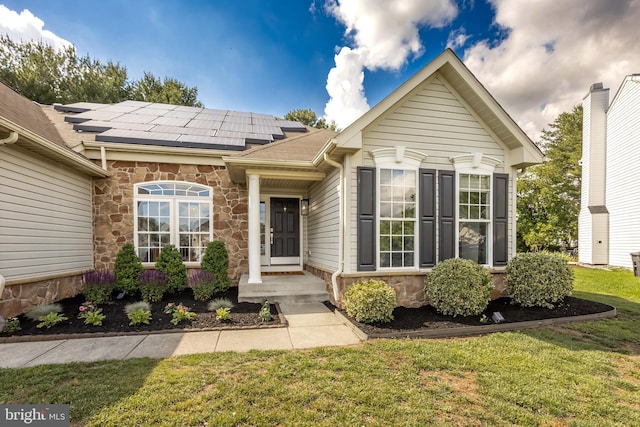 9177 Drawbridge Dr, Delmar, MD 21875 - view of front of home featuring stone siding, roof mounted solar panels, a front lawn, and roof with shingles