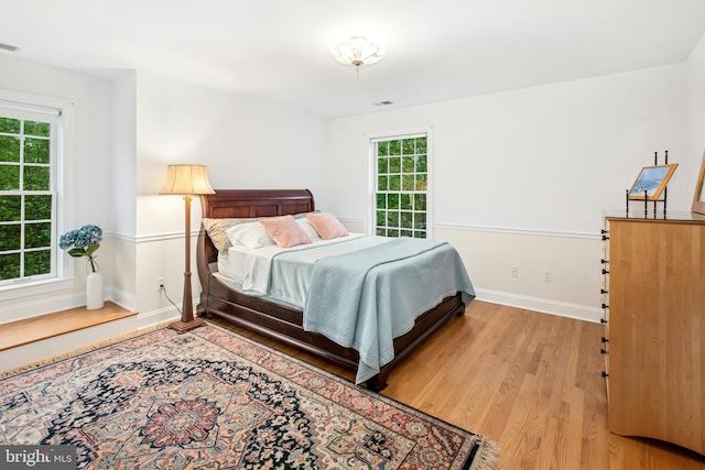 bedroom with wood finished floors, multiple windows, and baseboards