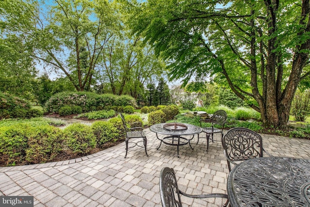 view of patio featuring a fire pit and view of wooded area
