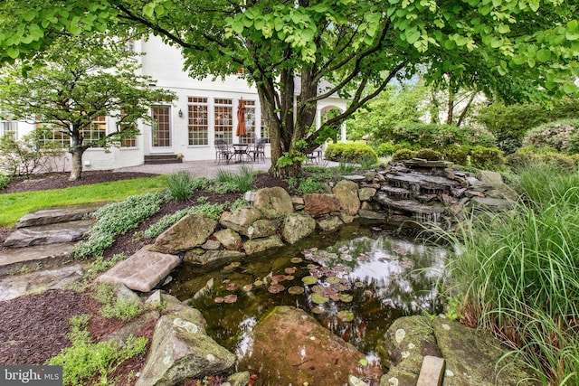 view of yard featuring a small pond and a patio