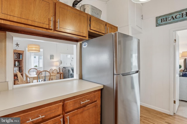 398 Kingfisher Rd, Tuckerton, NJ 08087 - kitchen with freestanding refrigerator, light countertops, light wood-style flooring, brown cabinetry, and baseboards