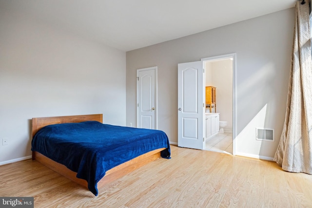 bedroom with wood finished floors, baseboards, and ensuite bath