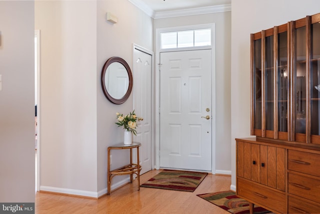 foyer entrance featuring crown molding, light wood-style flooring, and baseboards