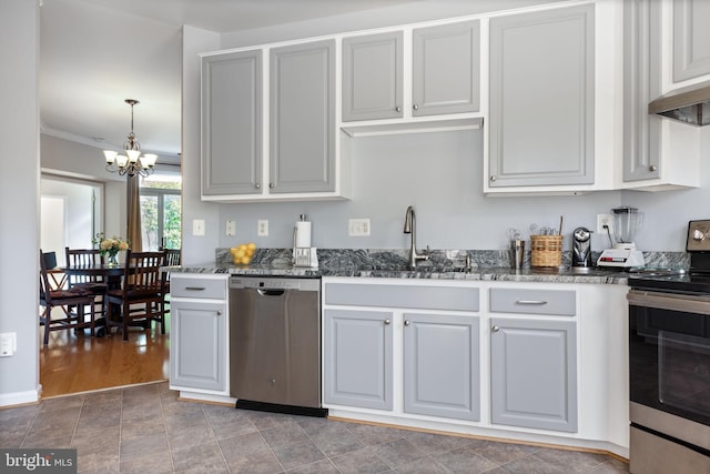 kitchen featuring stainless steel appliances, a sink, a chandelier, dark stone counters, and wall chimney exhaust hood