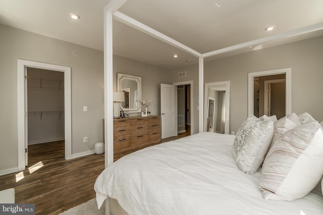 bedroom featuring a spacious closet, dark wood-type flooring, baseboards, recessed lighting, and a closet