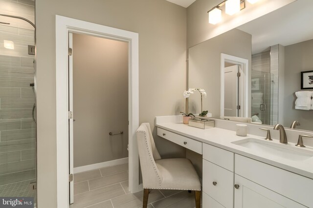 bathroom with a shower stall, vanity, tile patterned floors, and baseboards