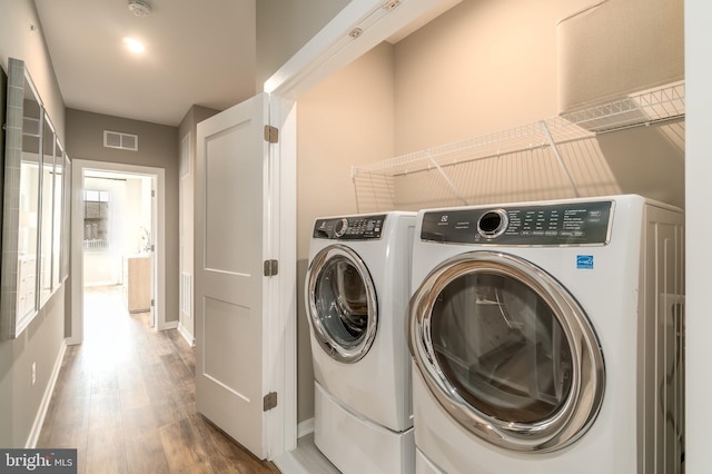 laundry area with washer and clothes dryer, light wood-style flooring, and baseboards