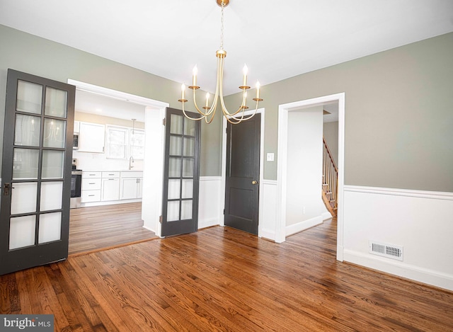 803 Essex Ave, Essex, MD 21221 - empty room with a chandelier, wood finished floors, french doors, stairway, and a wainscoted wall