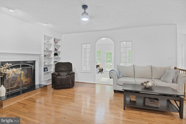 310 Owings Hill Ct, Owings, MD 20736 - living area featuring built in features, a premium fireplace, wood finished floors, baseboards, and arched walkways