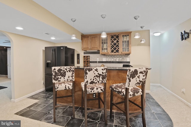 310 Owings Hill Ct, Owings, MD 20736 - kitchen with black refrigerator with ice dispenser, a kitchen bar, dark countertops, tasteful backsplash, and arched walkways