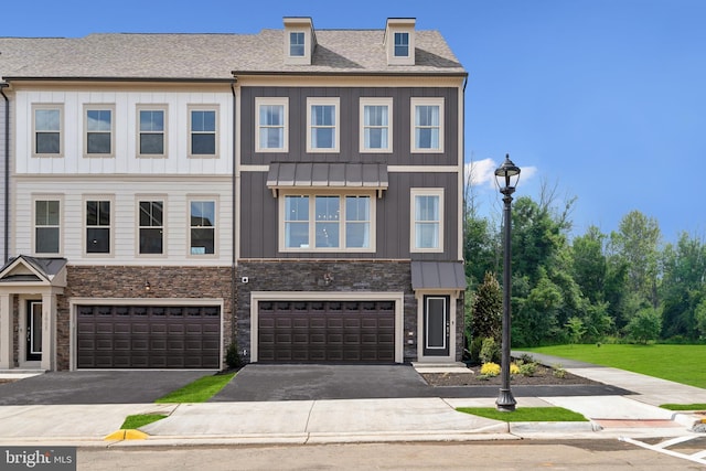 townhome / multi-family property featuring stone siding, driveway, a garage, and board and batten siding