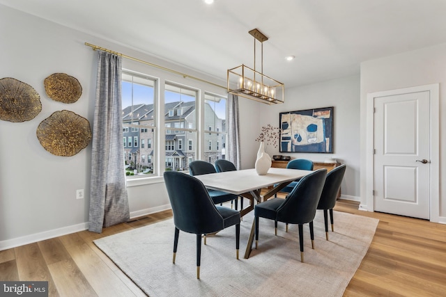 dining space with a chandelier, plenty of natural light, light wood finished floors, and baseboards