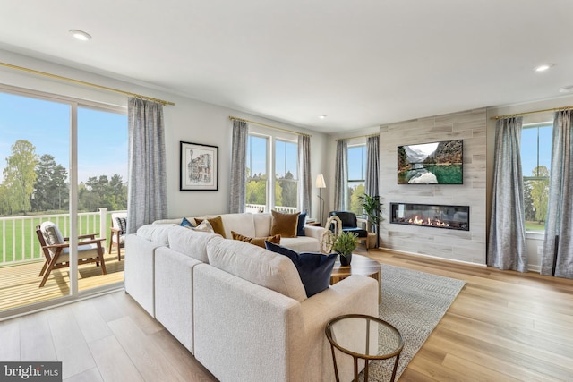 living room featuring healthy amount of natural light, a large fireplace, light wood-style flooring, and recessed lighting