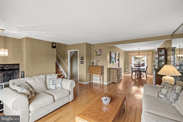 24 Holyoke Dr, Delran, NJ 08075 - living room with a chandelier, wood finished floors, stairs, a brick fireplace, and baseboards