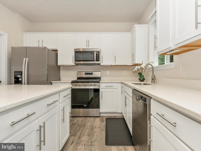 5809 Zoe Ln, Frederick, MD 21704 - kitchen with stainless steel appliances, a sink, white cabinets, light wood-style floors, and light stone counters