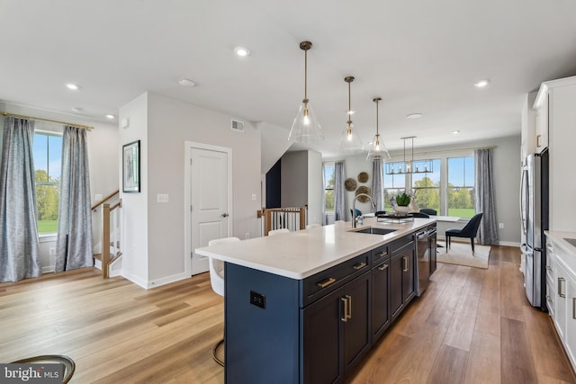kitchen with a sink, appliances with stainless steel finishes, light countertops, light wood-style flooring, and recessed lighting