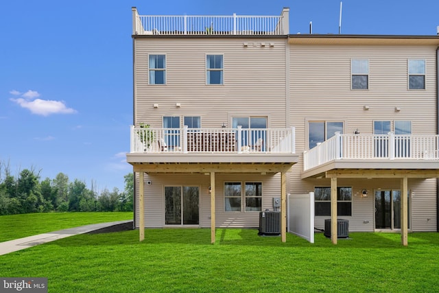 rear view of house featuring central AC and a lawn