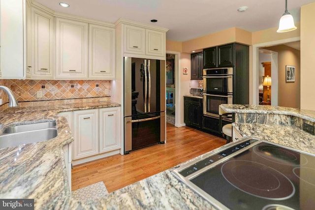 3097 Mill Rd, Doylestown, PA 18902 - kitchen featuring stainless steel appliances, a sink, light wood finished floors, light stone counters, and pendant lighting