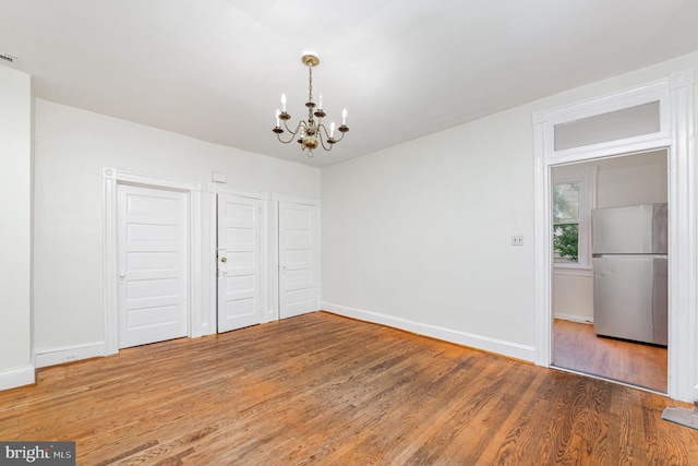 unfurnished dining area with a chandelier, light wood-type flooring, and baseboards