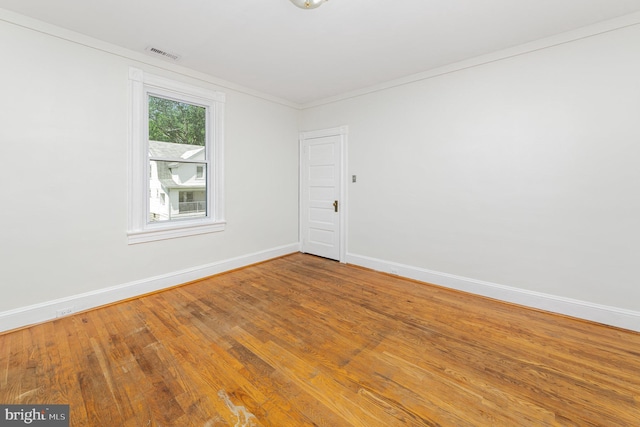 empty room featuring baseboards, wood finished floors, and ornamental molding