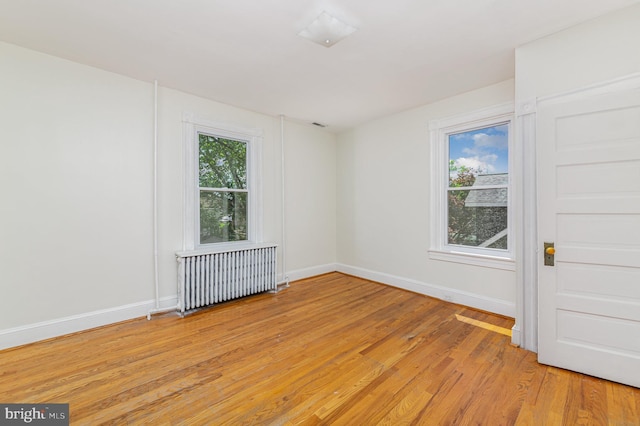 unfurnished room with radiator, light wood-type flooring, and baseboards