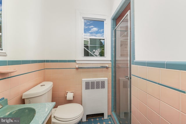full bathroom featuring radiator, tile walls, a stall shower, wainscoting, and toilet
