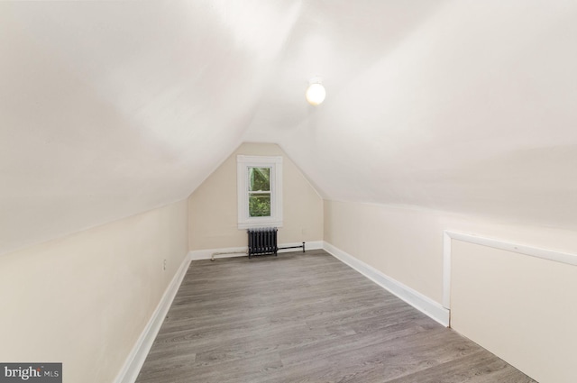 bonus room with wood finished floors, vaulted ceiling, and baseboards