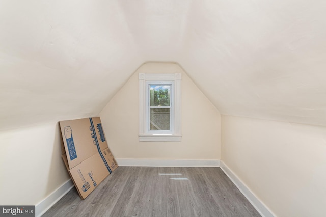 additional living space featuring wood finished floors, lofted ceiling, and baseboards