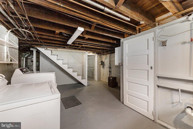 unfinished below grade area featuring washing machine and clothes dryer and stairway