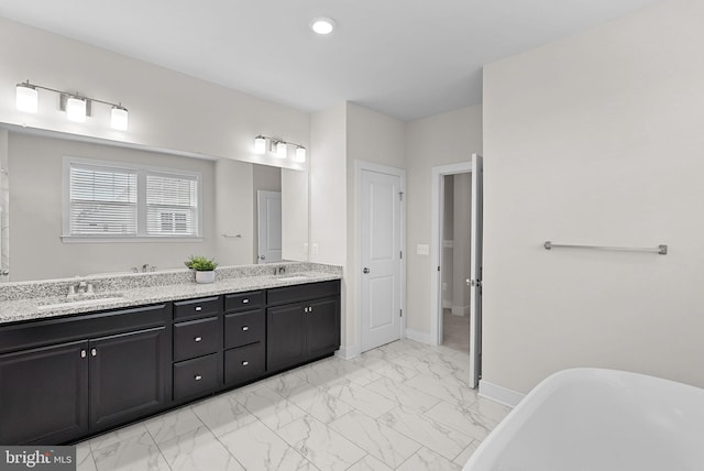 19253 Running Spring Ct, Leesburg, VA 20175 - bathroom featuring a freestanding bath, double vanity, marble look tiles, baseboards, and recessed lighting