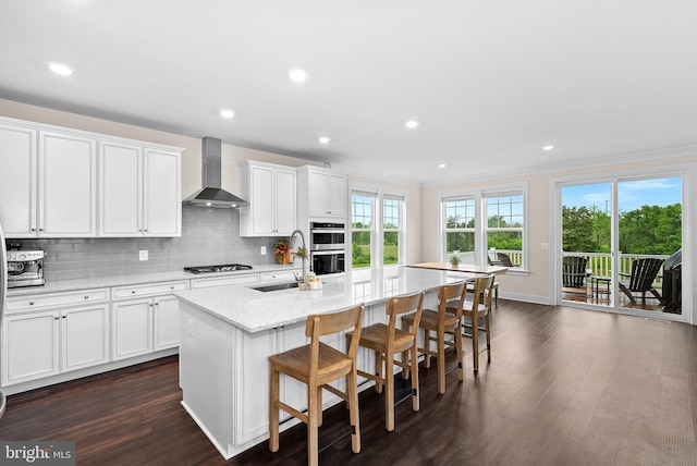 19253 Running Spring Ct, Leesburg, VA 20175 - kitchen featuring wall chimney range hood, a sink, double oven, gas stovetop, and a center island with sink