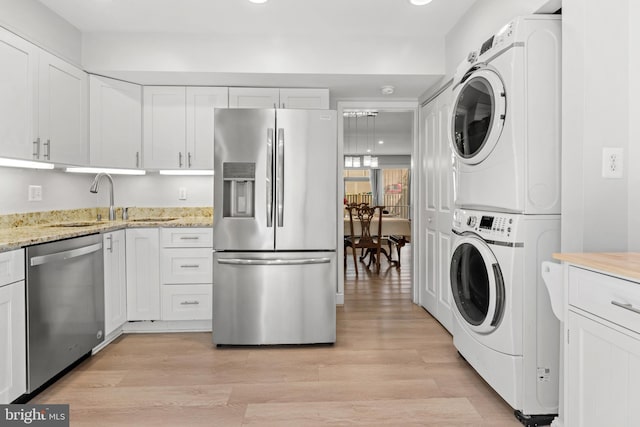 7374 Park Heights Ave, Baltimore, MD 21208 - kitchen with stainless steel appliances, stacked washing machine and dryer, a sink, light wood finished floors, and recessed lighting