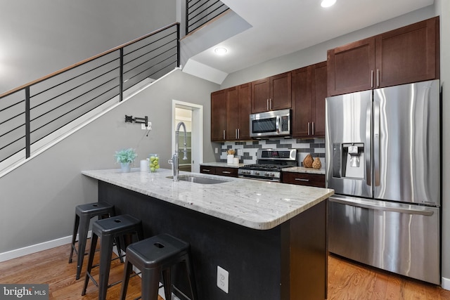1423 1st St NW Unit B, Washington, DC 20001 - kitchen with appliances with stainless steel finishes, a sink, a breakfast bar area, light wood-style flooring, and dark brown cabinetry